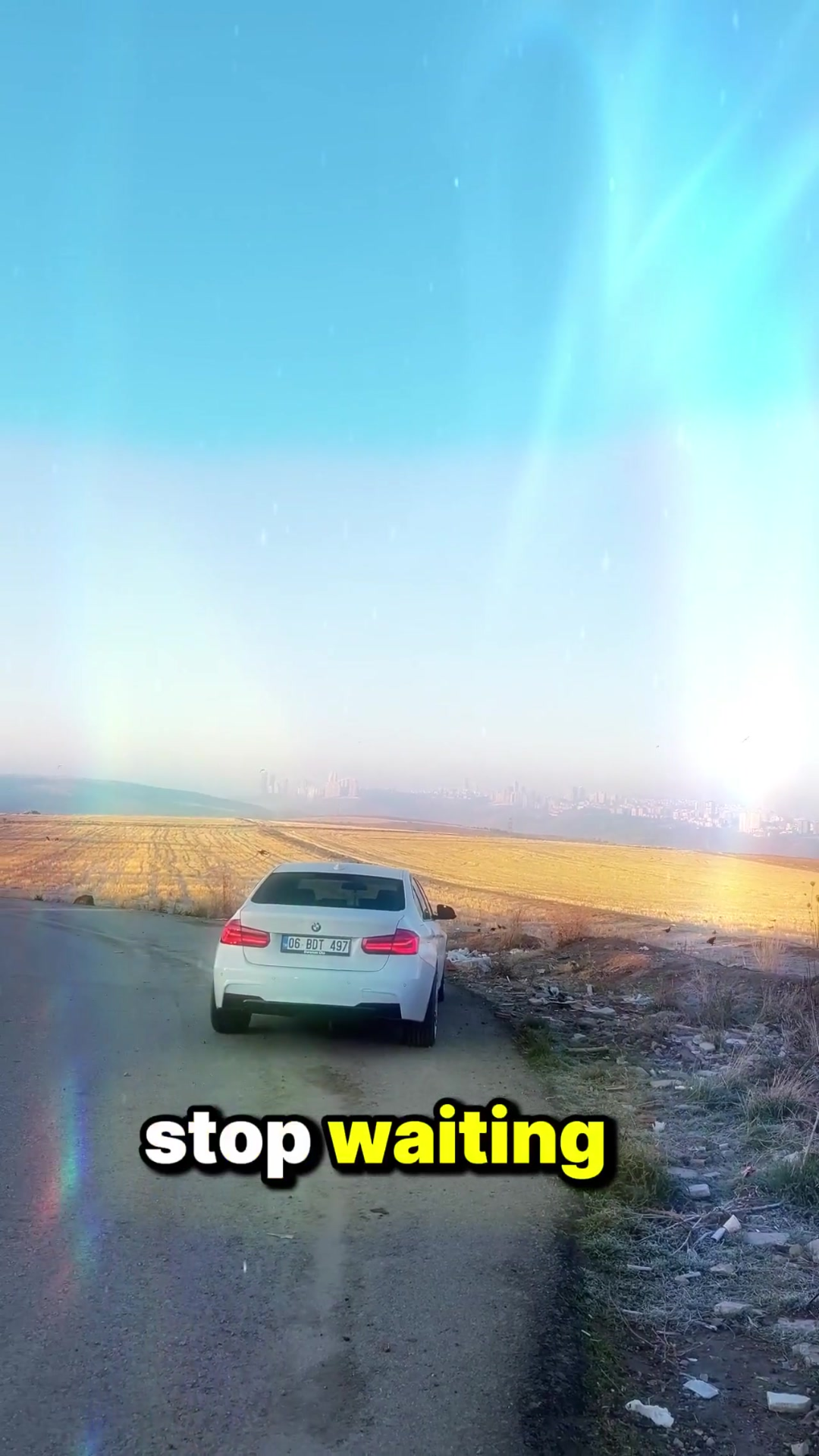 White BMW on a country road with stop waiting text overlay